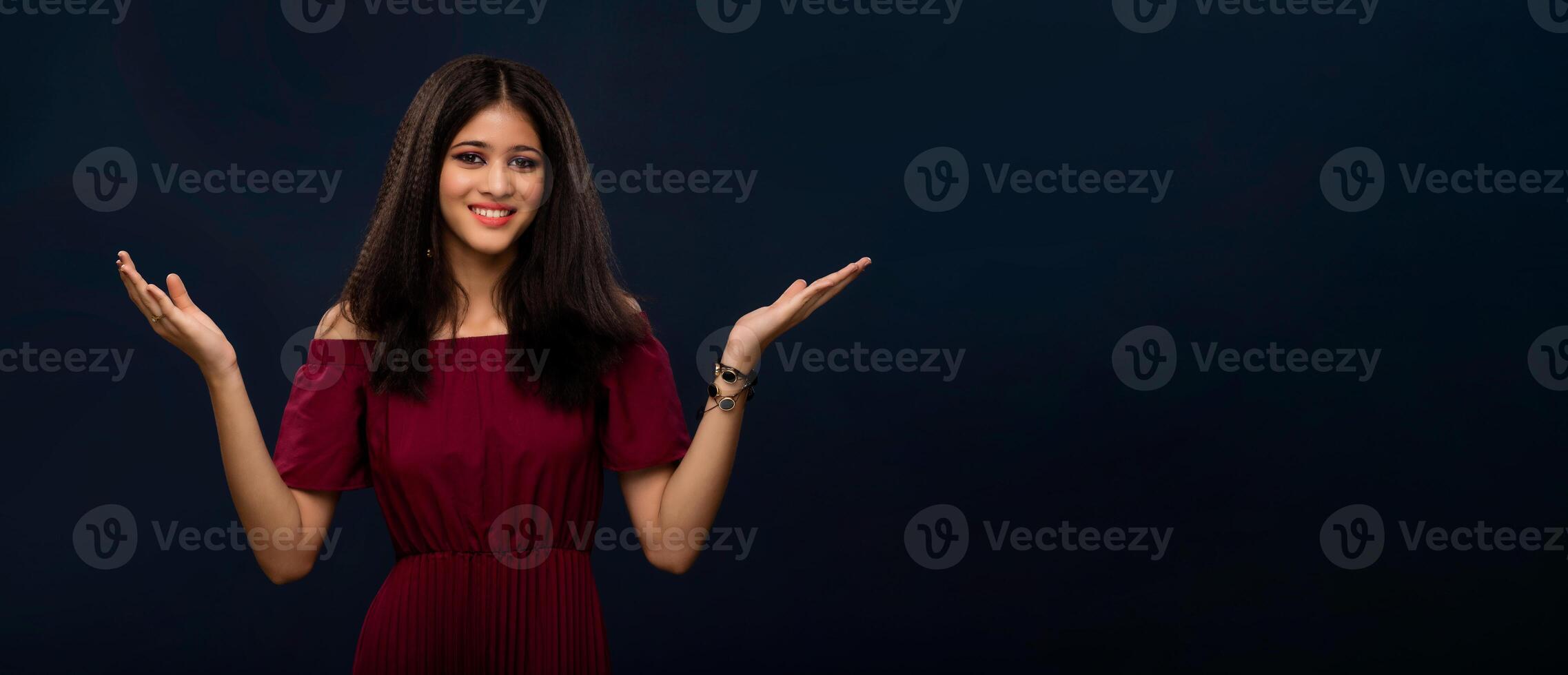 Portrait of beautiful young girl presenting something, showing copy space on her palm on a grey background photo