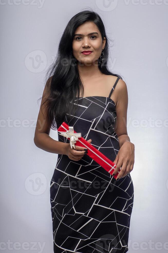 Portrait of a pretty young girl posing with gift box on grey background. photo
