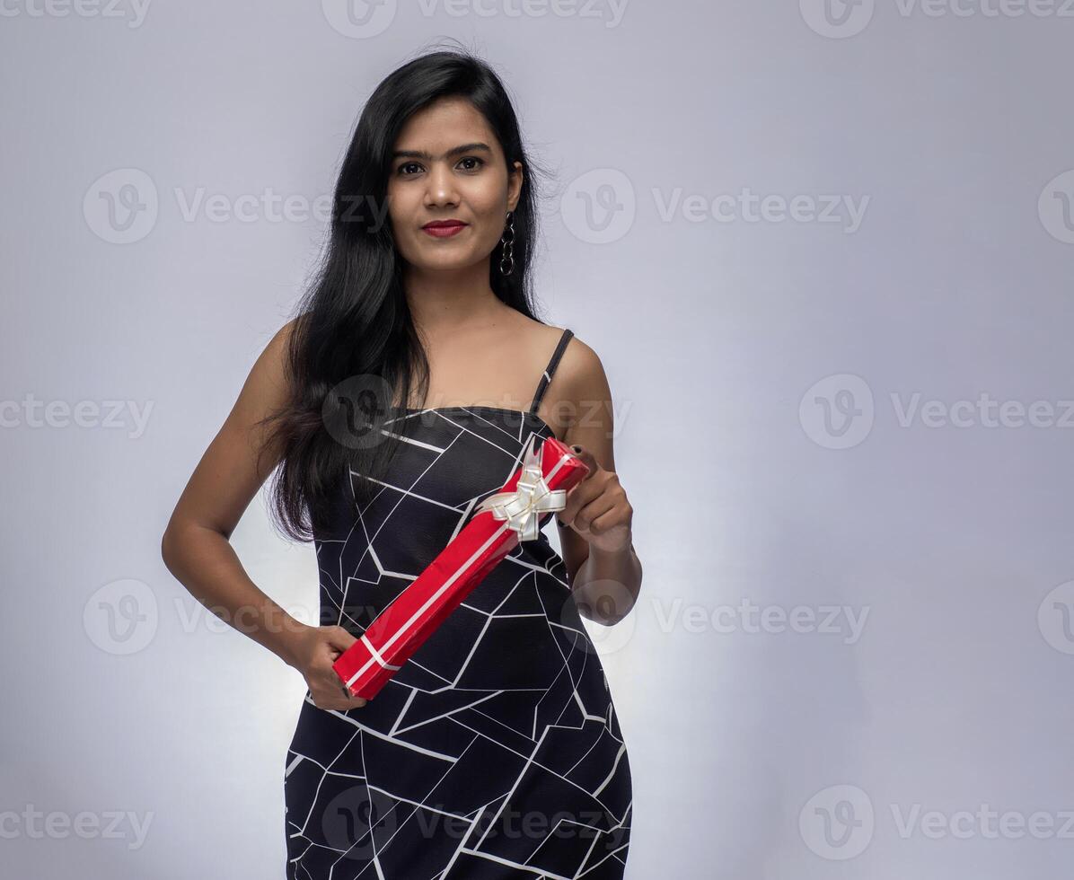 Portrait of a pretty young girl posing with gift box on grey background. photo