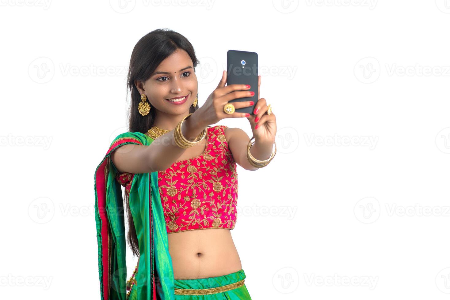 Young Indian girl using a mobile phone or smartphone, talking selfie or talking on chat isolated on a white background photo