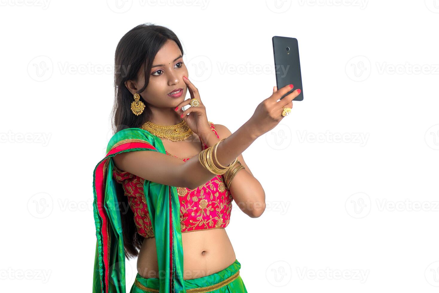 Young Indian girl using a mobile phone or smartphone, talking selfie or talking on chat isolated on a white background photo