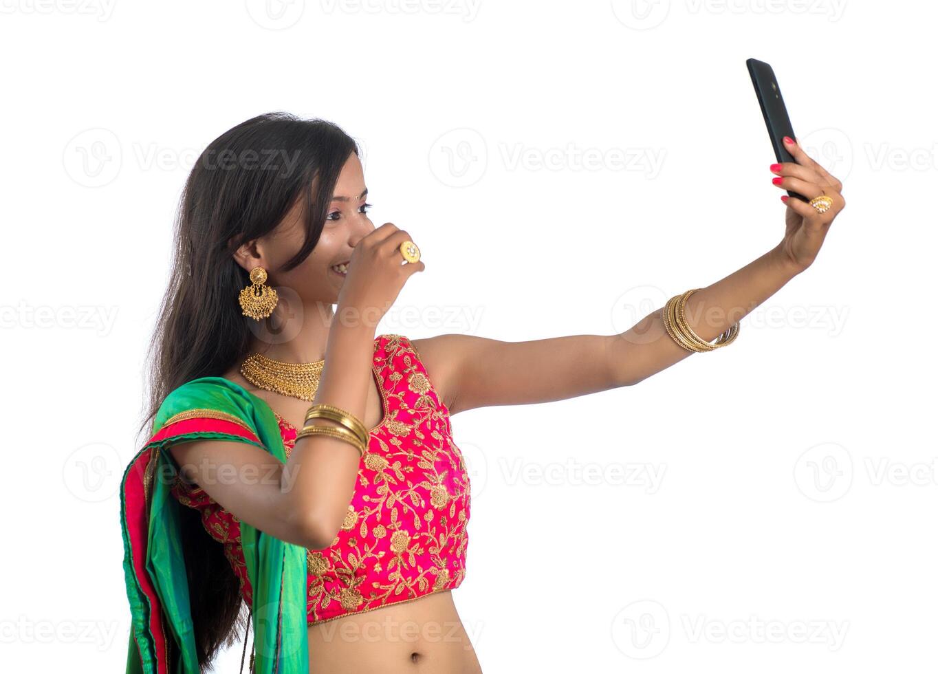 Young Indian girl using a mobile phone or smartphone, talking selfie or talking on chat isolated on a white background photo