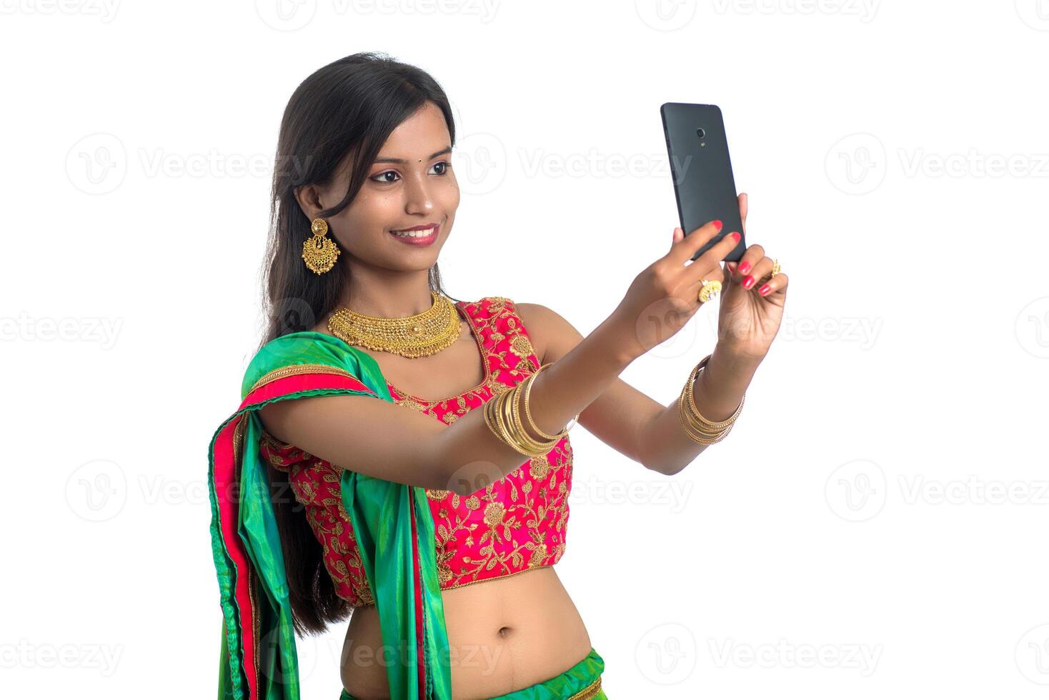 Young Indian girl using a mobile phone or smartphone, talking selfie or talking on chat isolated on a white background photo