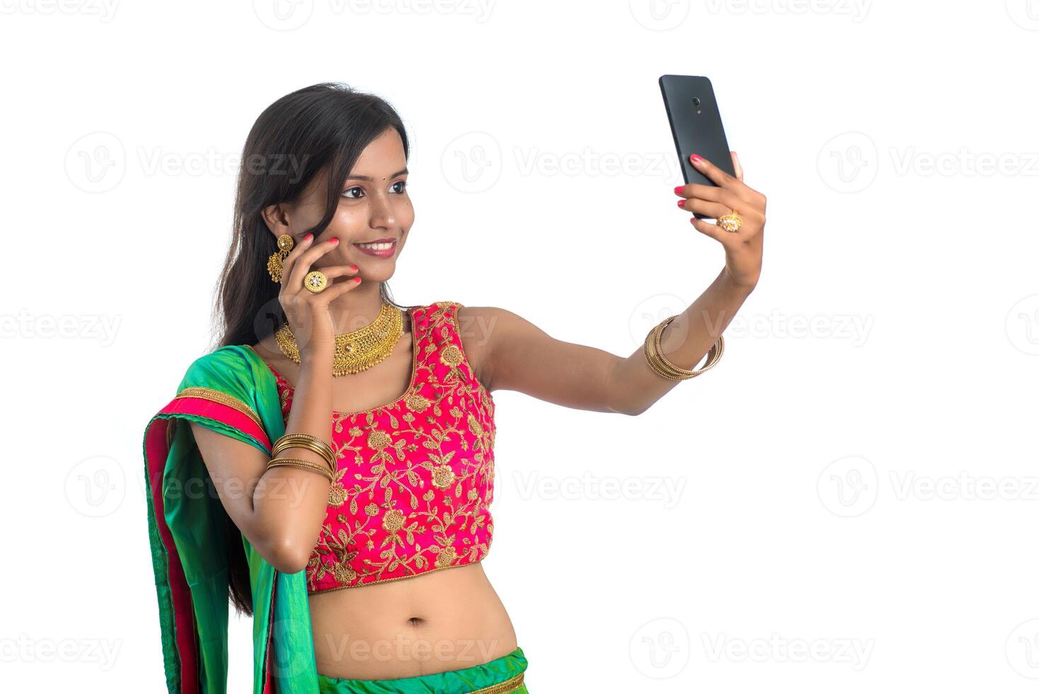 Young Indian girl using a mobile phone or smartphone, talking selfie or talking on chat isolated on a white background photo
