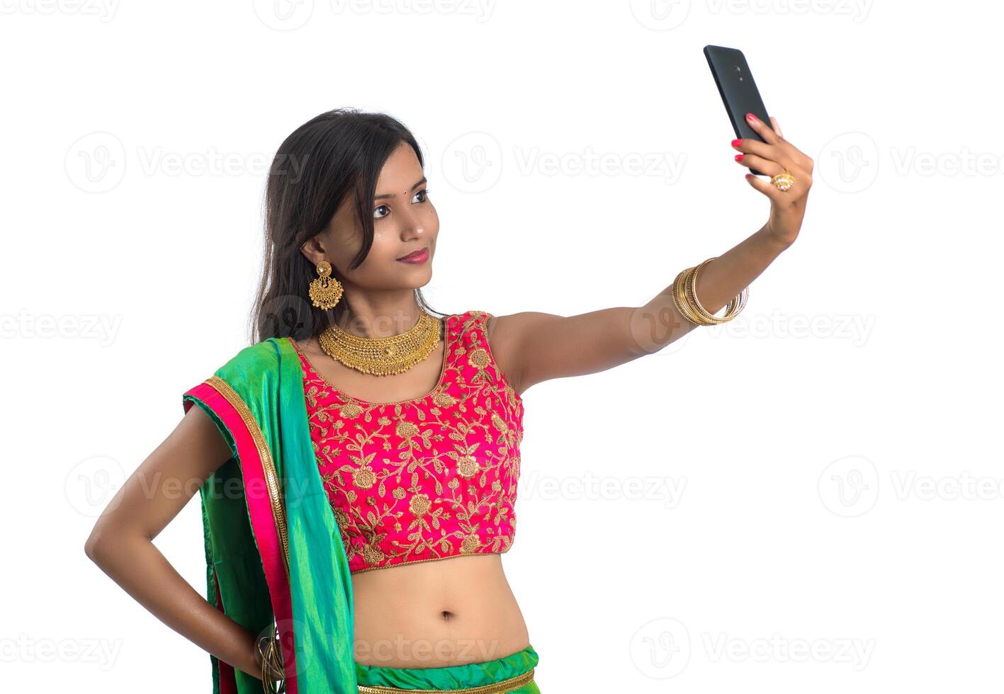 Young Indian girl using a mobile phone or smartphone, talking selfie or talking on chat isolated on a white background photo
