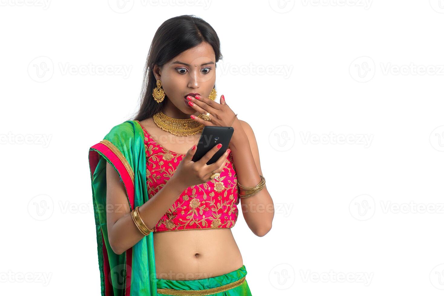 Young Indian traditional girl using a mobile phone or smartphone isolated on a white background photo