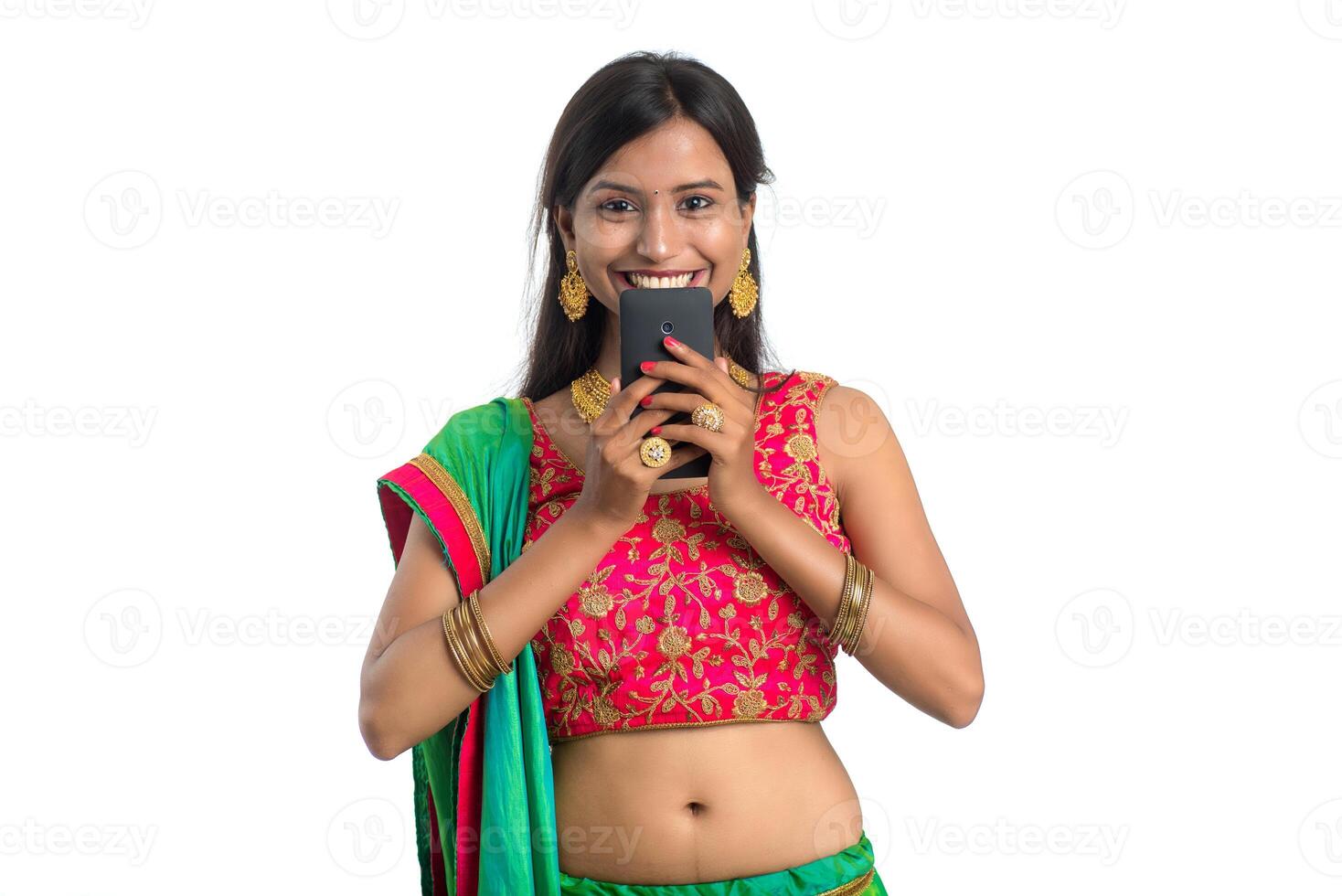Young Indian traditional girl using a mobile phone or smartphone isolated on a white background photo