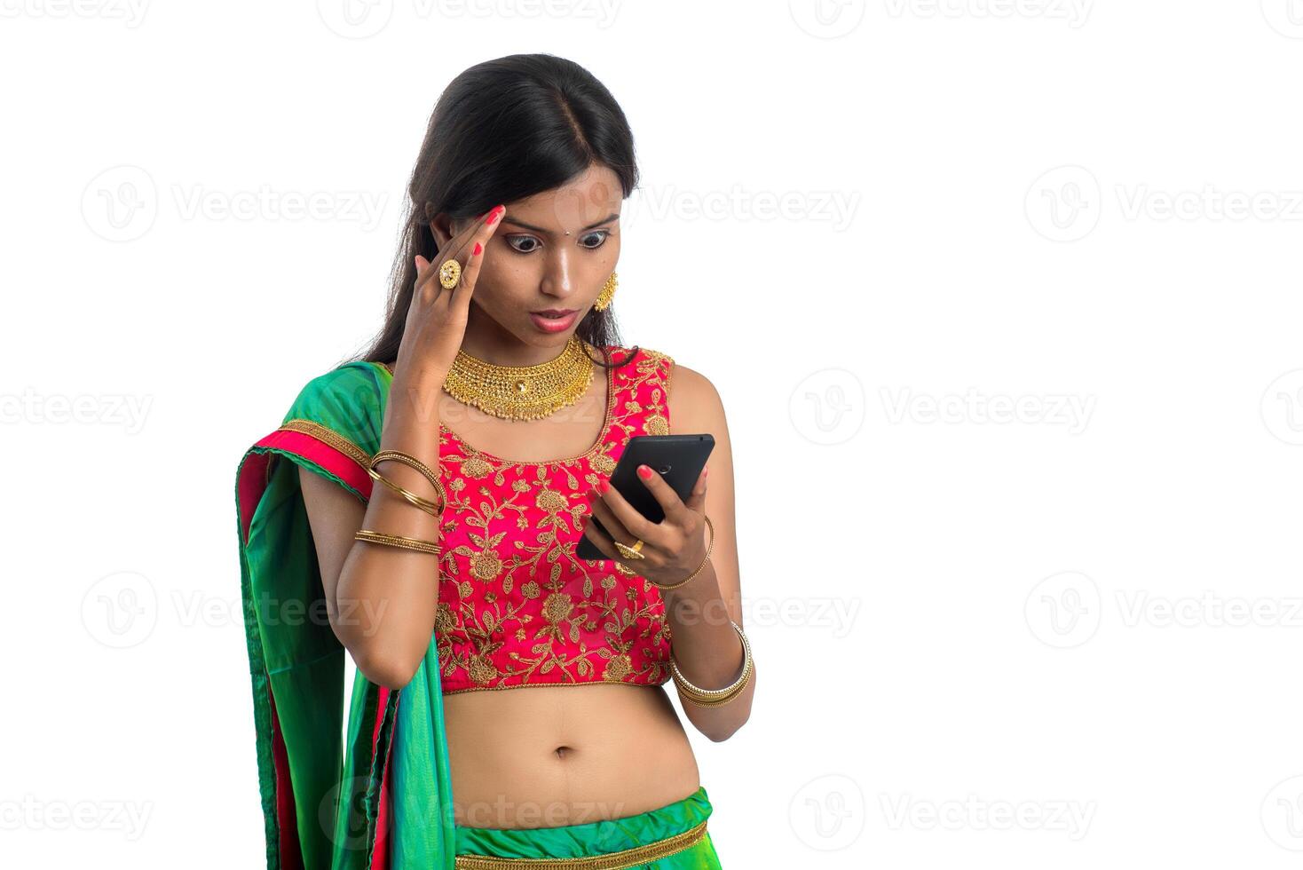 Young Indian traditional girl using a mobile phone or smartphone isolated on a white background photo