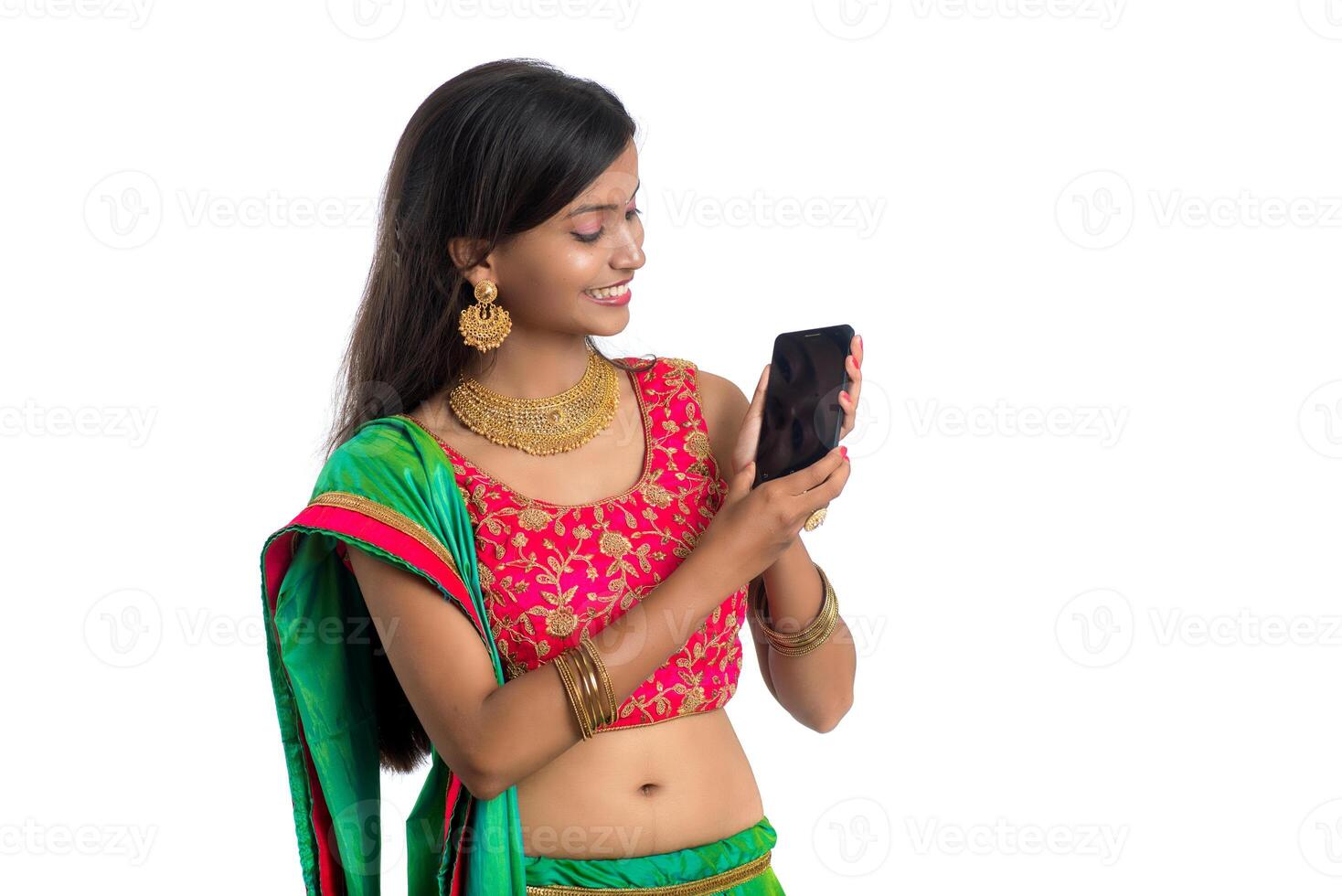 Young Indian traditional girl using a mobile phone or smartphone isolated on a white background photo