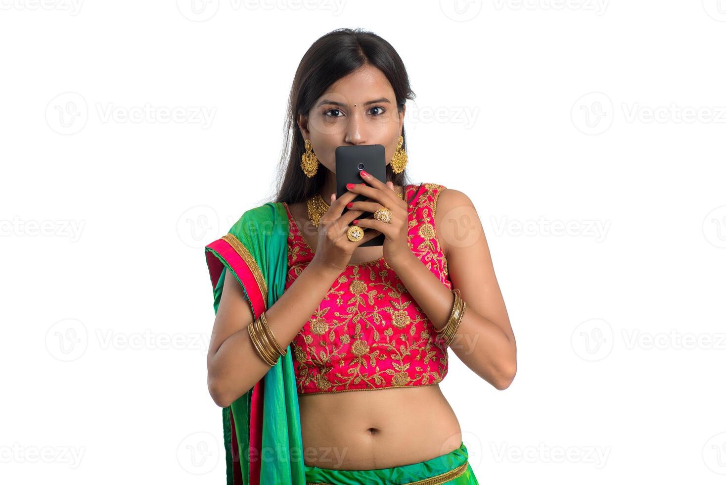 Young Indian traditional girl using a mobile phone or smartphone isolated on a white background photo