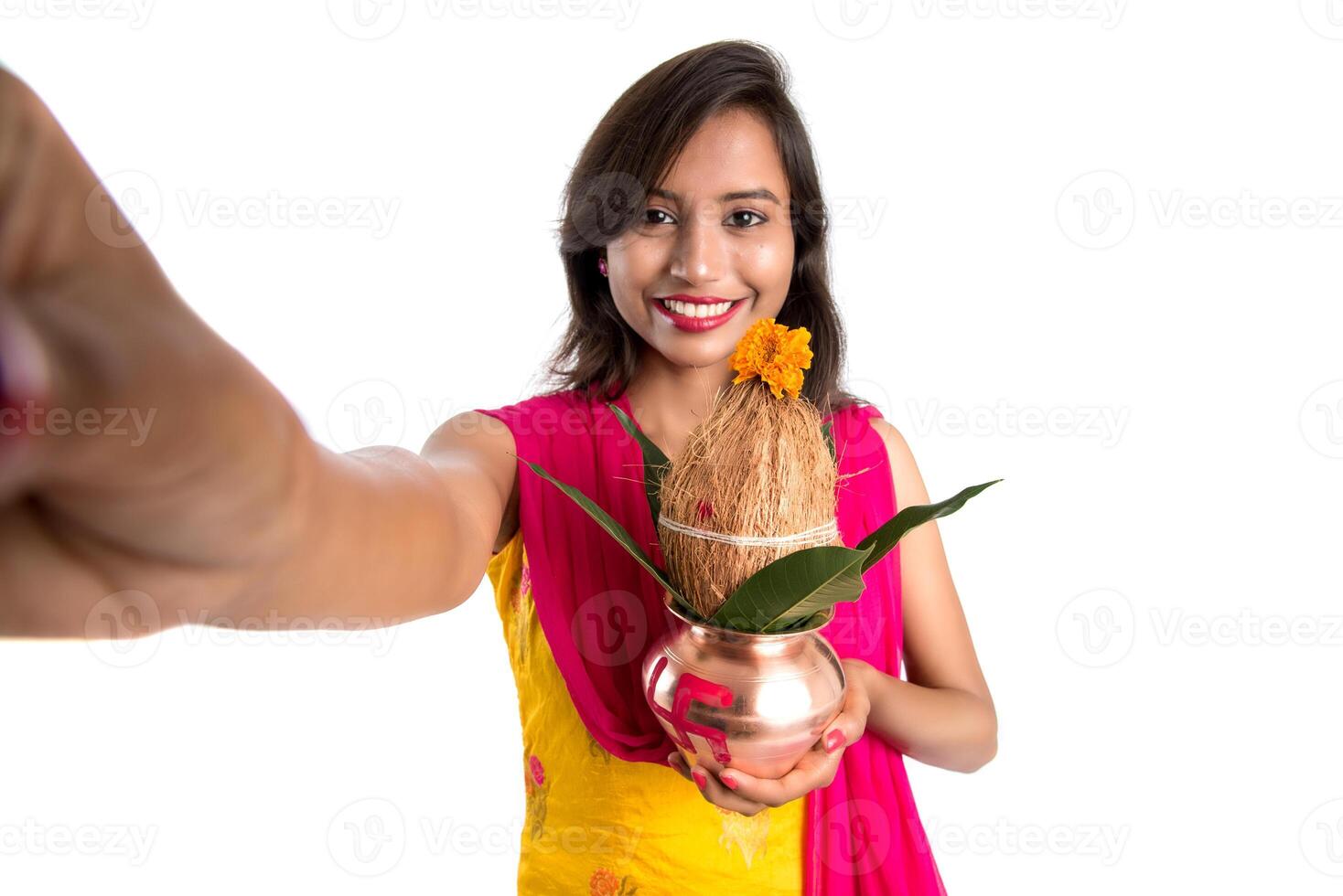 Beautiful young happy girl taking selfie with Kalash using a camera or smartphone on a white background photo