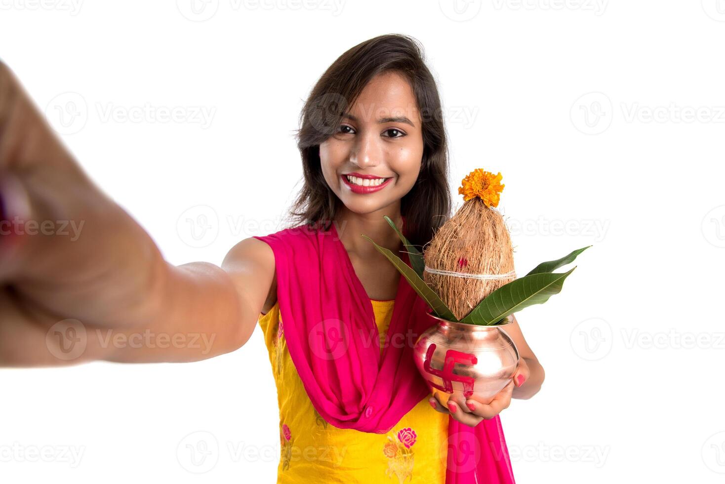 Beautiful young happy girl taking selfie with Kalash using a camera or smartphone on a white background photo