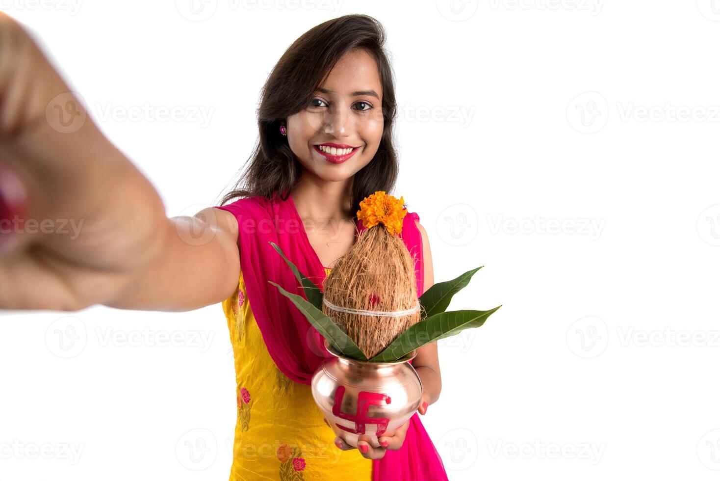 Beautiful young happy girl taking selfie with Kalash using a camera or smartphone on a white background photo