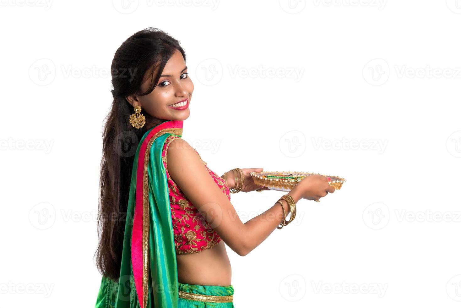 Portrait of a Indian Traditional Girl holding Diya, Girl Celebrating Diwali or Deepavali with holding oil lamp during festival of light on white background photo