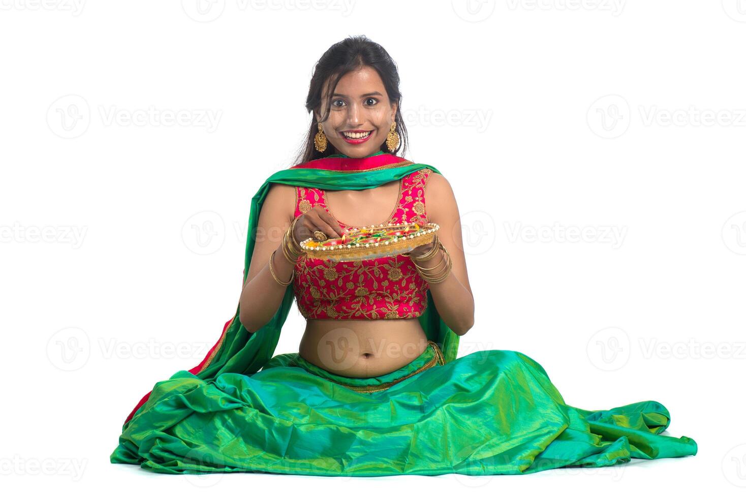 Portrait of a Indian Traditional Girl holding Diya, Girl Celebrating Diwali or Deepavali with holding oil lamp during festival of light on white background photo