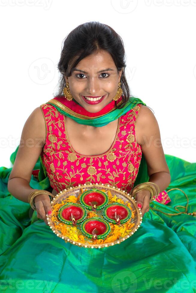Portrait of a Indian Traditional Girl holding Diya, Girl Celebrating Diwali or Deepavali with holding oil lamp during festival of light on white background photo