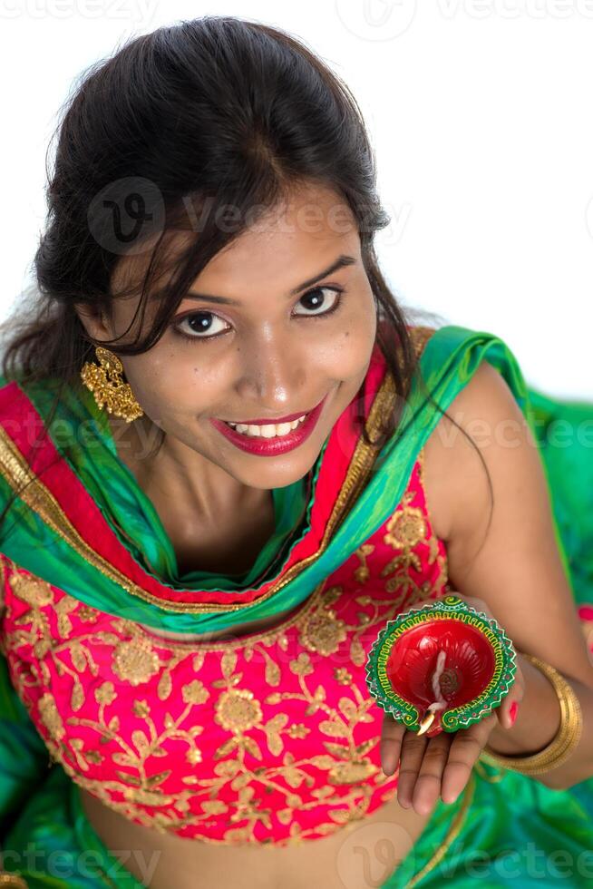 Portrait of a Indian Traditional Girl holding Diya, Girl Celebrating Diwali or Deepavali with holding oil lamp during festival of light on white background photo