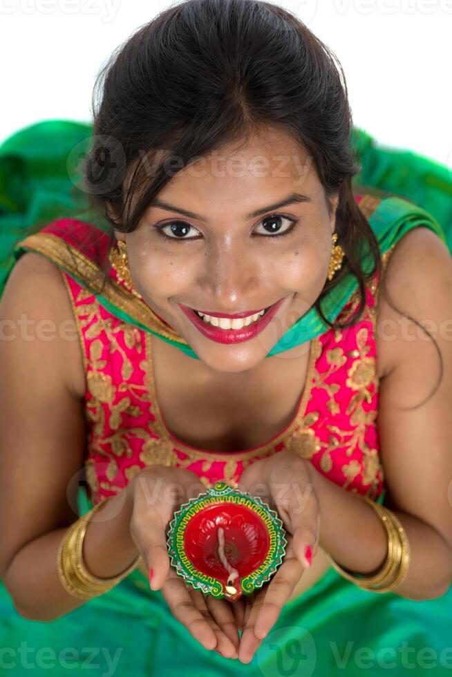 Portrait of a Indian Traditional Girl holding Diya, Girl Celebrating Diwali or Deepavali with holding oil lamp during festival of light on white background photo
