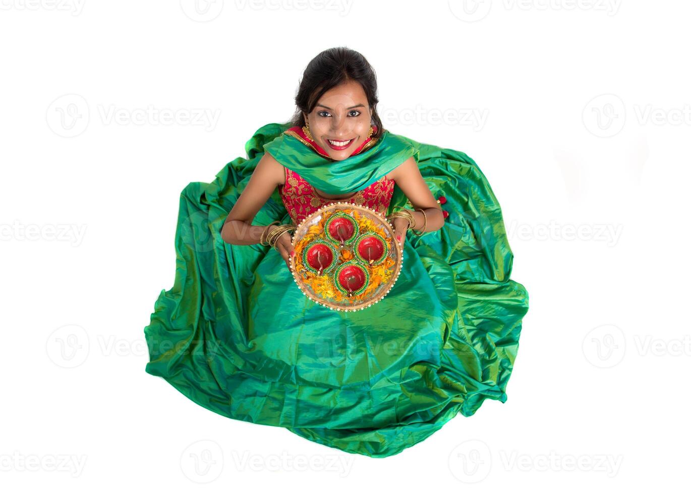 Portrait of a Indian Traditional Girl holding Diya, Girl Celebrating Diwali or Deepavali with holding oil lamp during festival of light on white background photo