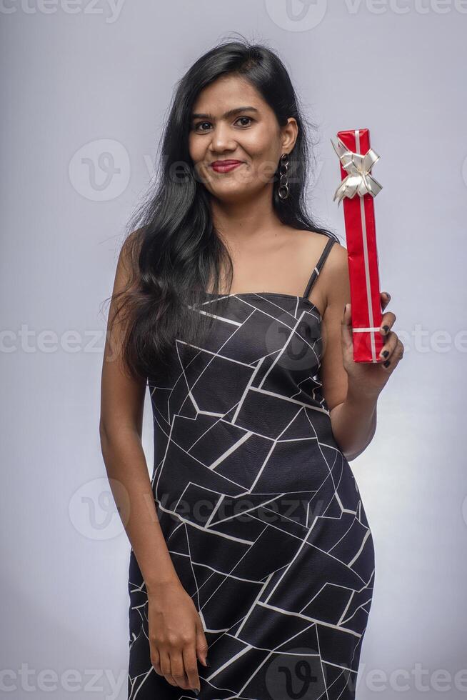 Portrait of a pretty young girl posing with gift box on grey background. photo