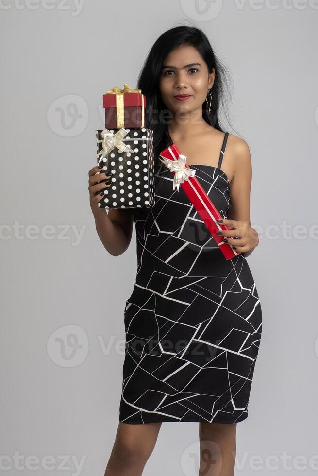 Portrait of a pretty young girl posing with gift box on grey background. photo