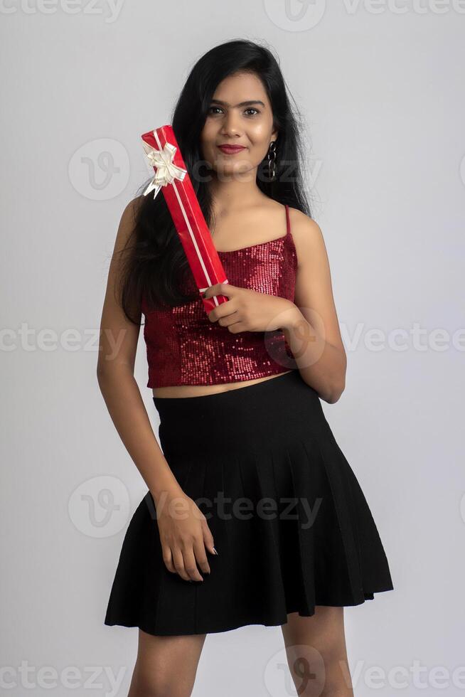 Portrait of a pretty young girl posing with gift box on grey background. photo