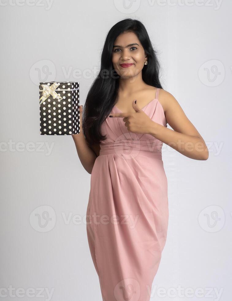 Portrait of a pretty young girl posing with gift box on grey background. photo