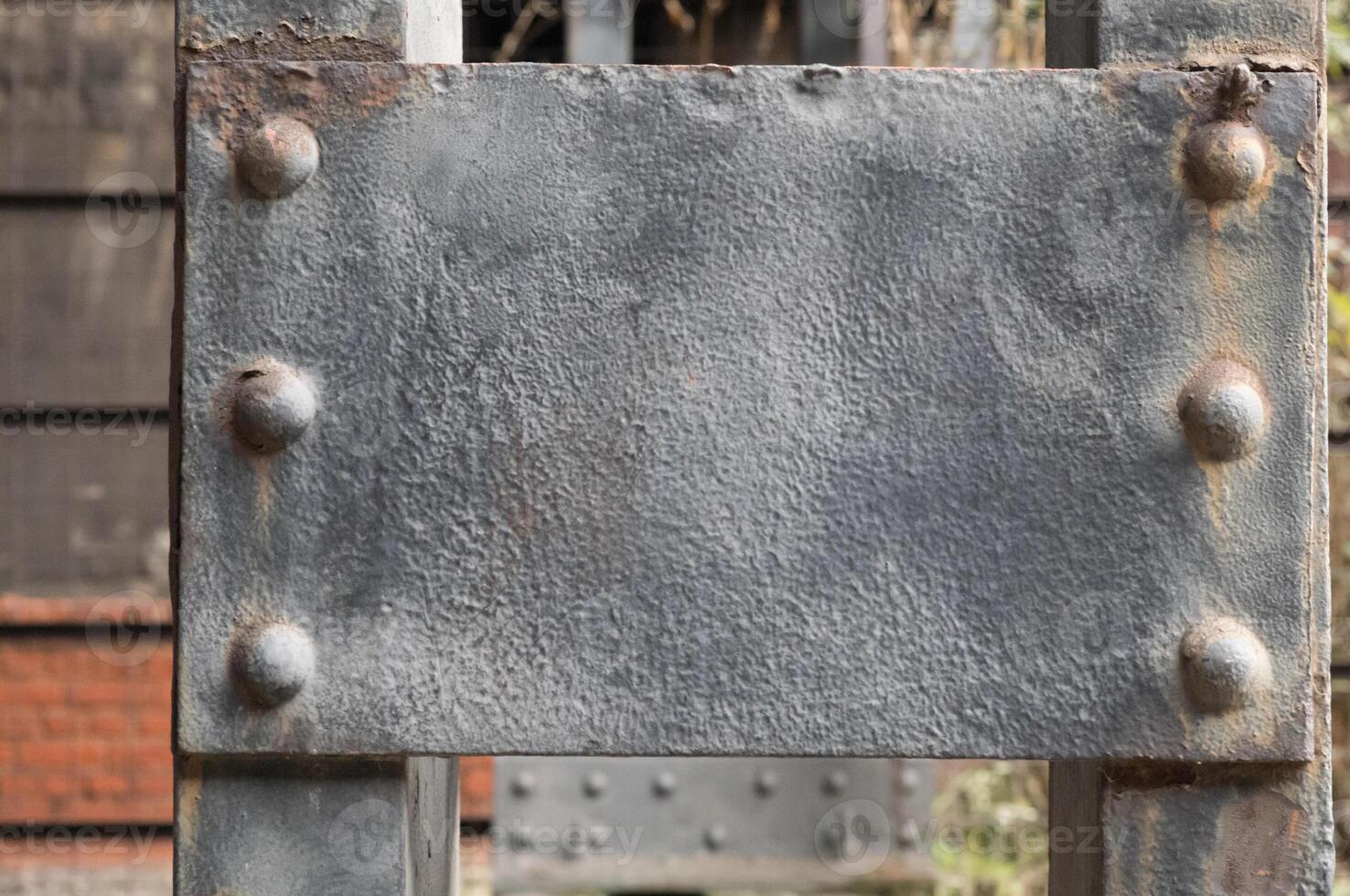 Rusty metal plate fixed with rivets on a metal structure photo