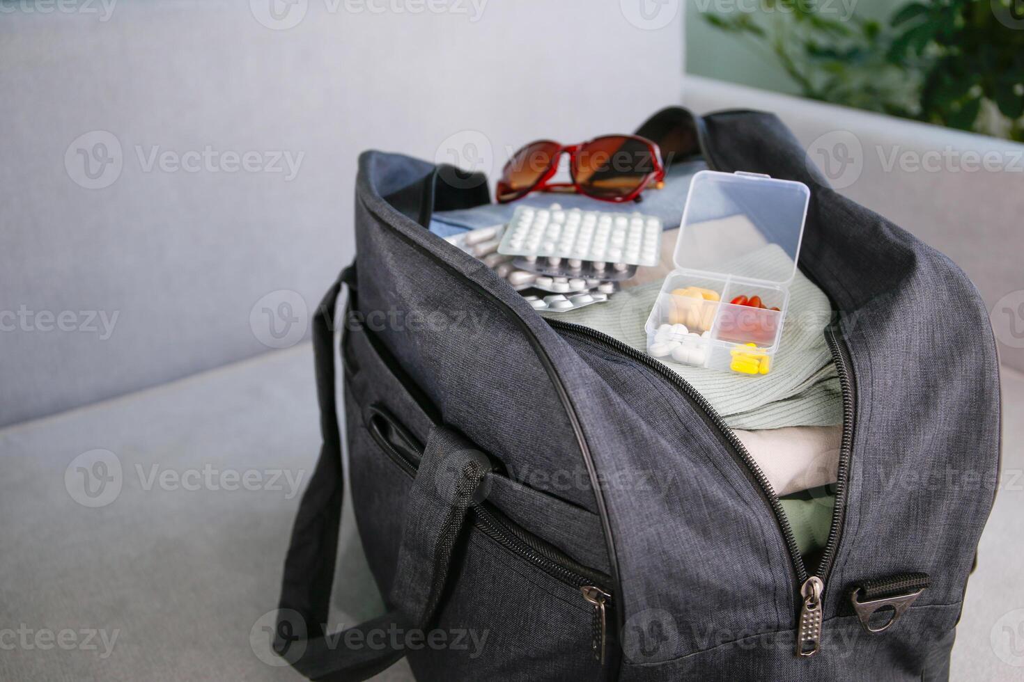 Clothes and pills in a travel bag. Concept of medication required in journey photo
