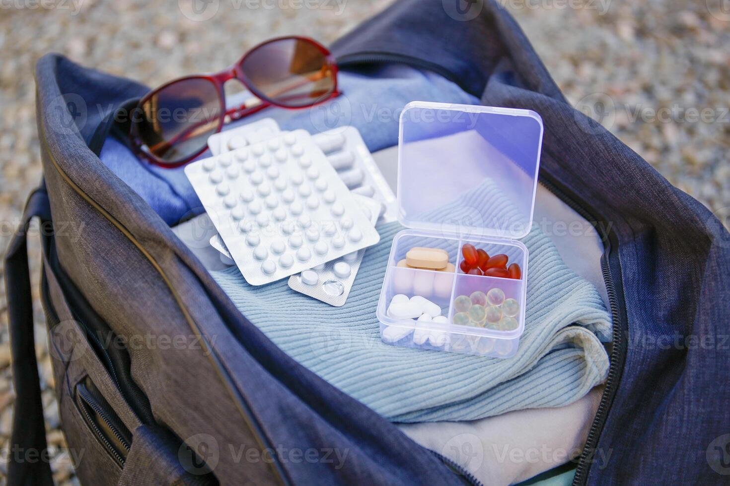 Clothes and pills in a travel bag. Concept of medication required in journey photo