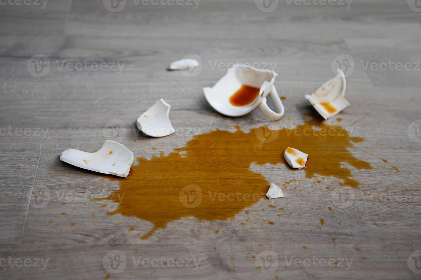 A broken cup of coffee fell on laminate, coffee spilled on floor. photo