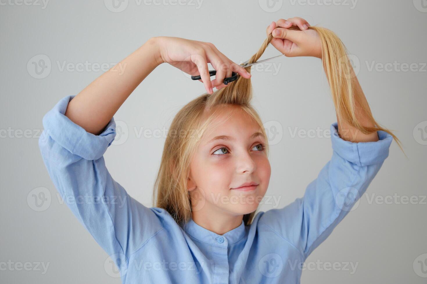 A girl cuts her long hair with scissors. photo