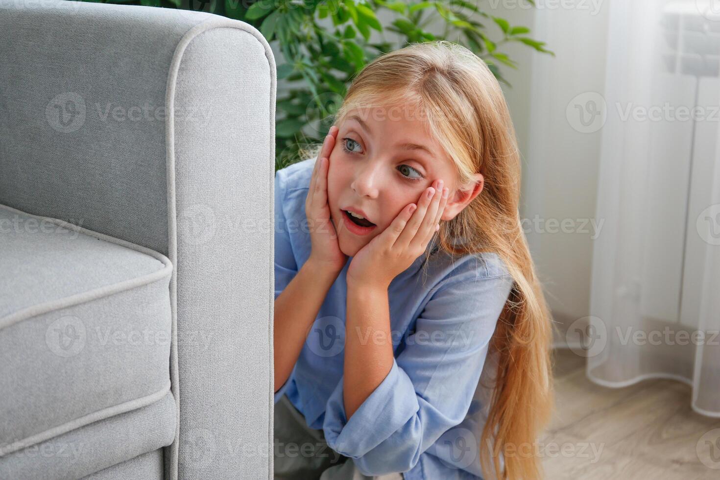 The girl is hiding behind the sofa and eavesdropping on someone else's conversation. photo