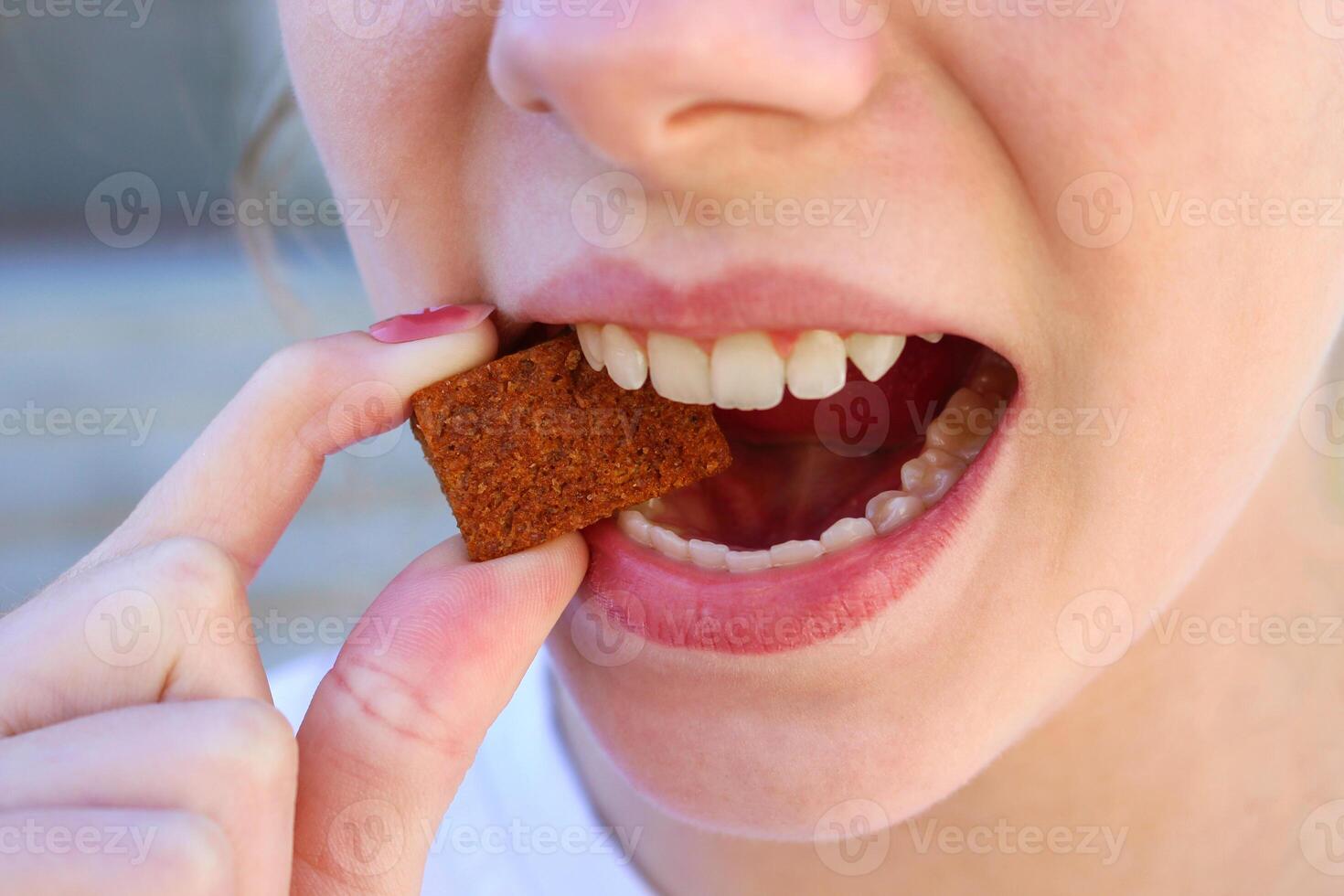 A teenager eats a cracker. Tooth enamel deteriorates. photo
