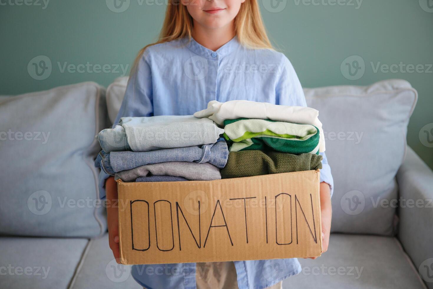 Girl holding donation box with with clothes. photo