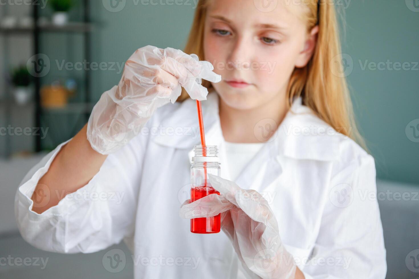 The girl conducts chemical experiments at home. Focus on flasks with red liquid. photo