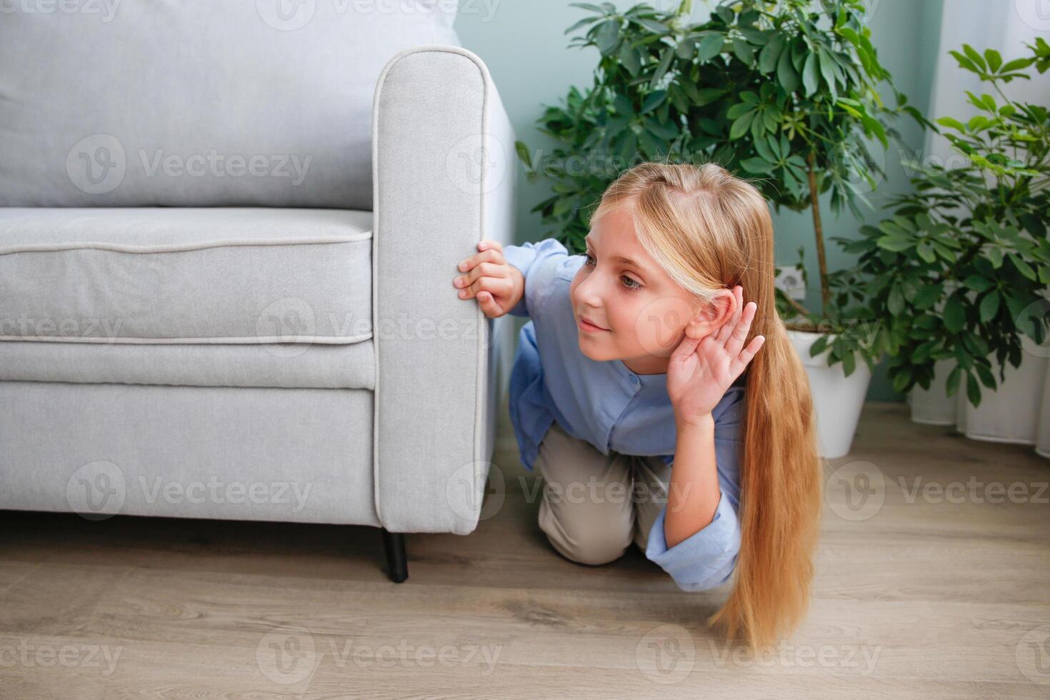 The girl is hiding behind the sofa and eavesdropping on someone else's conversation. photo