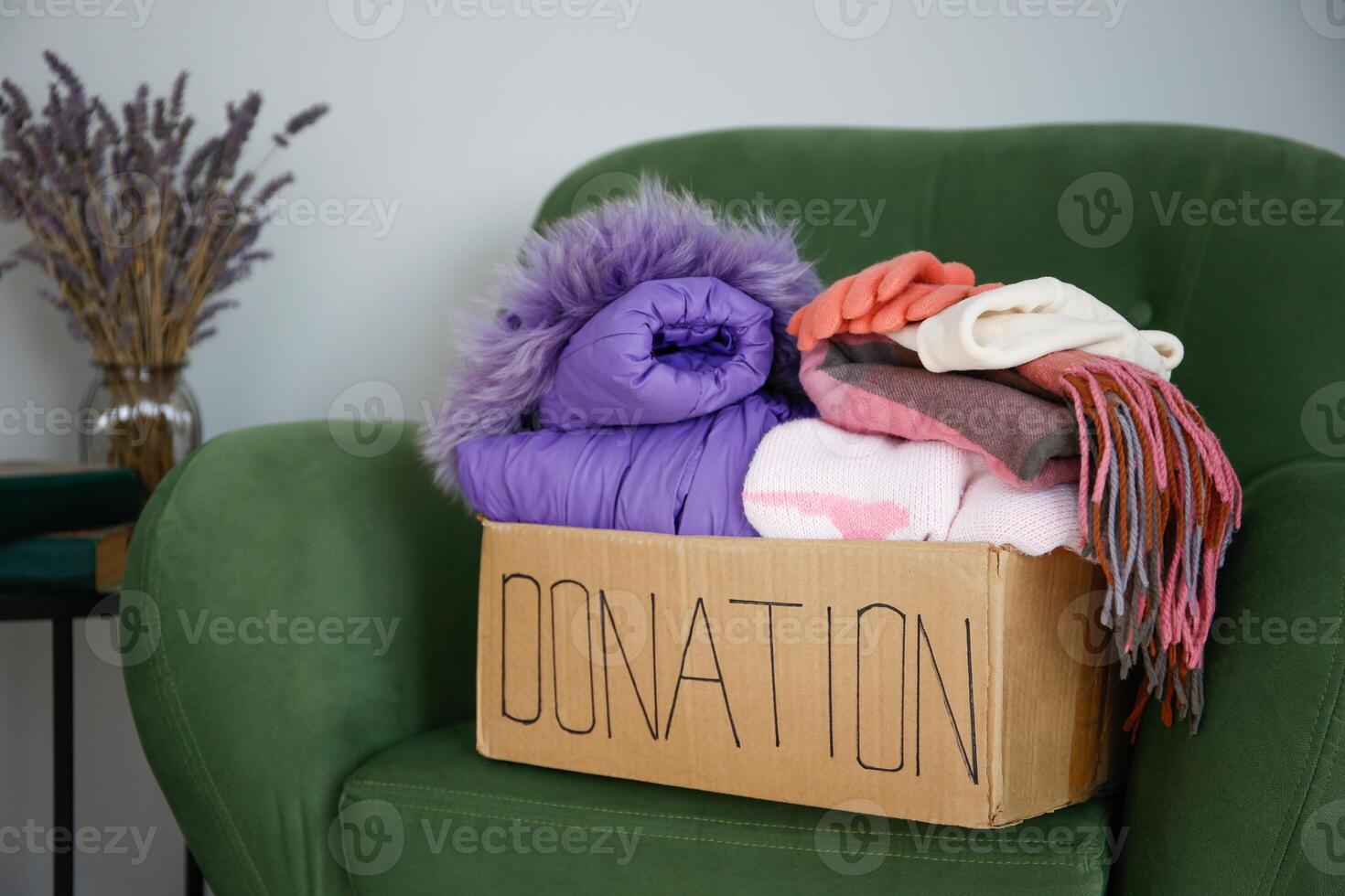 Donation box with clothes on the armchair in the living room. photo