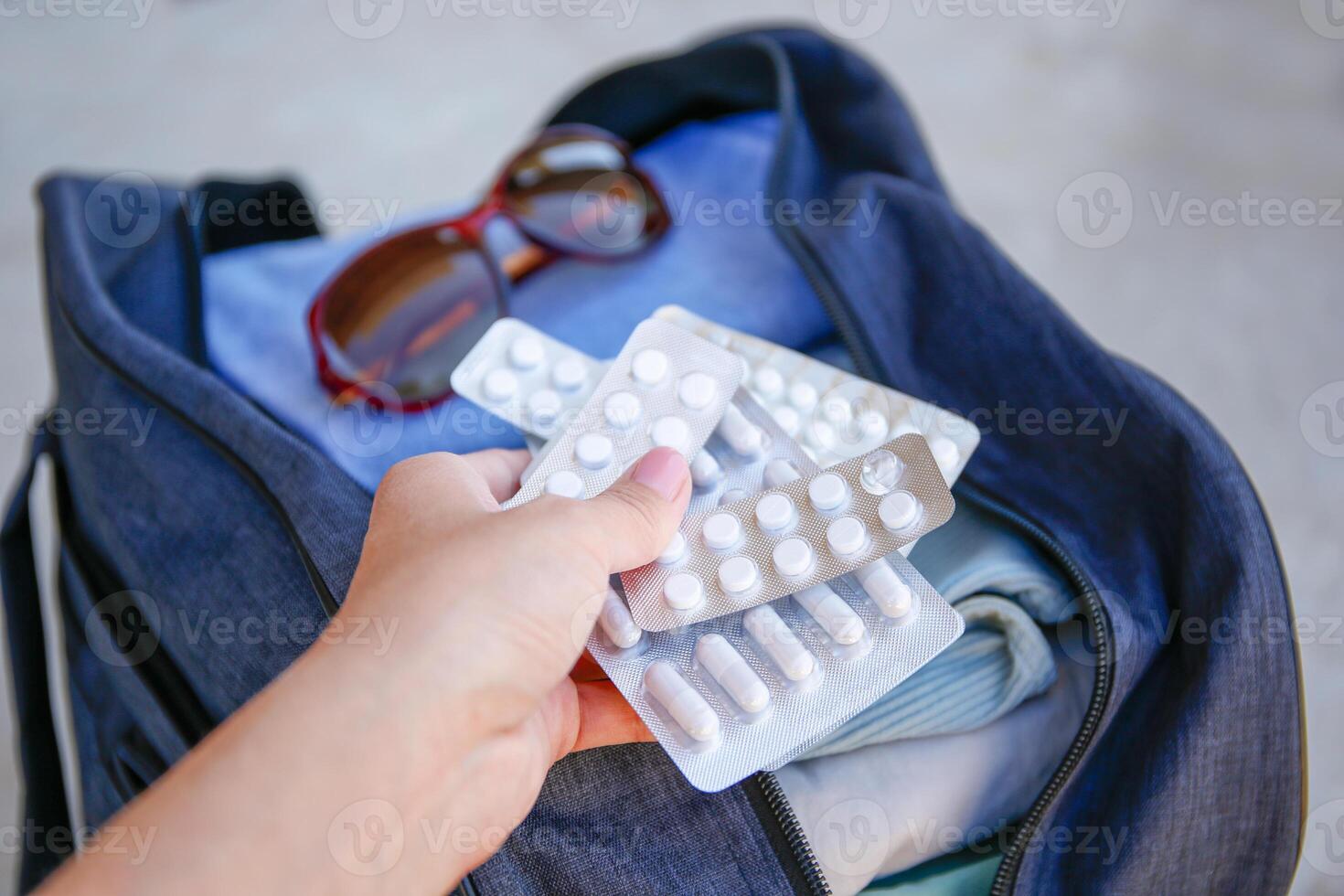 Clothes and pills in a travel bag. Concept of medication required in journey. photo