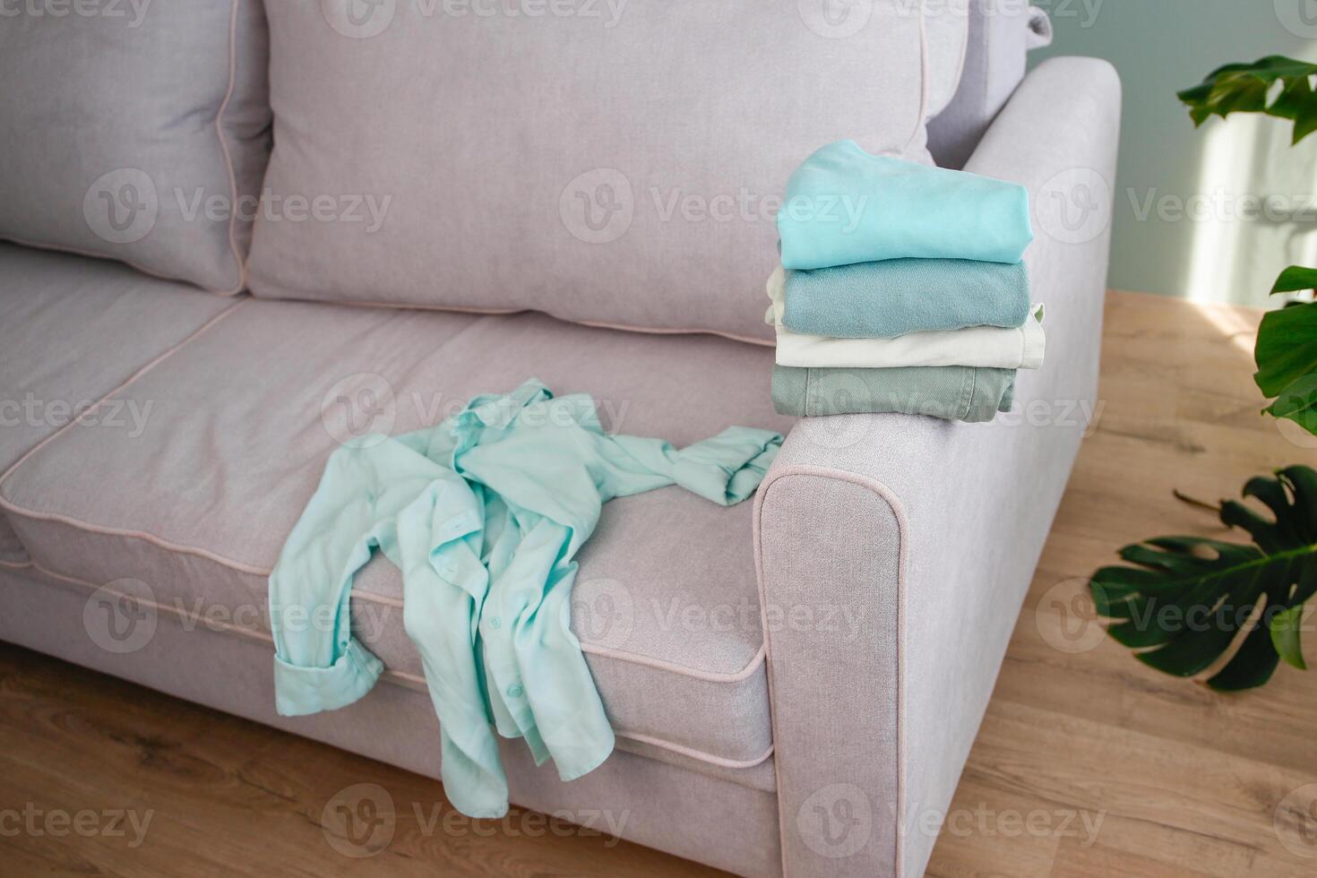 Pile of colorful warm clothes on the grey sofa. photo