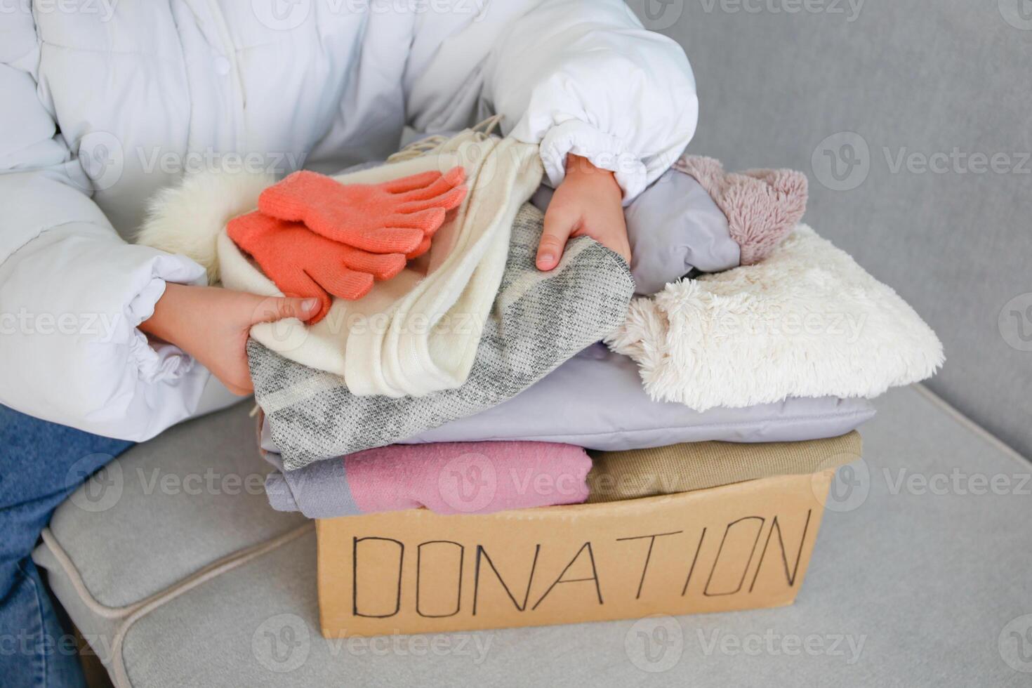 A child holds a donation box with clothes in the living room. photo