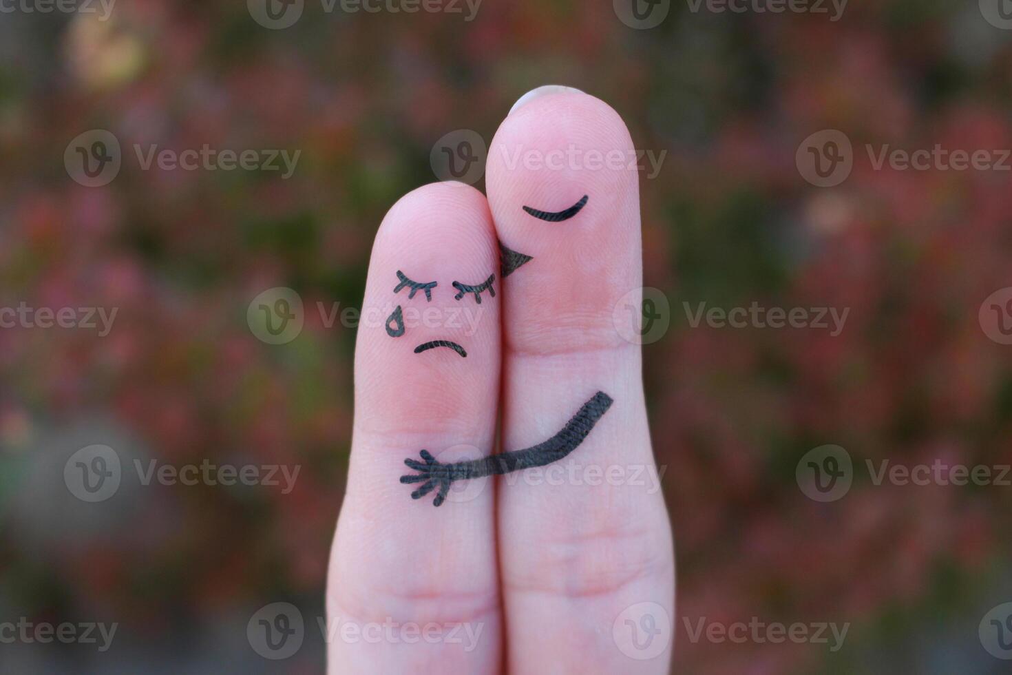Fingers art of displeased couple. Woman cries, man reassures her. He kisses and hugs her. photo