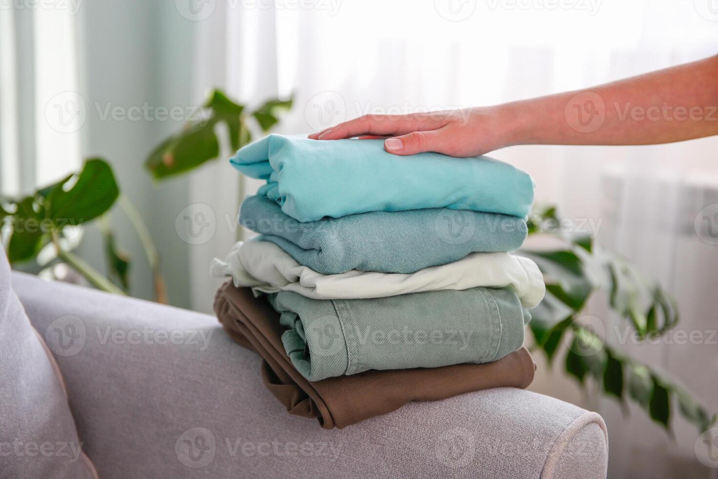 Pile of colorful warm clothes on the grey sofa. photo