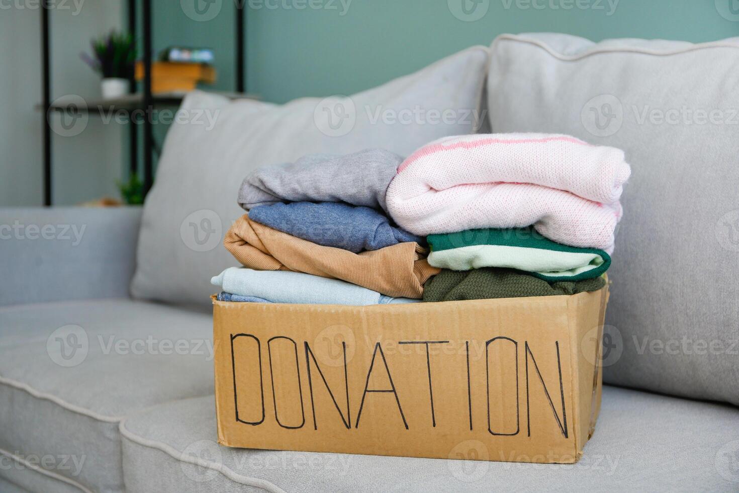 Donation box with clothes on the couch in the living room. photo