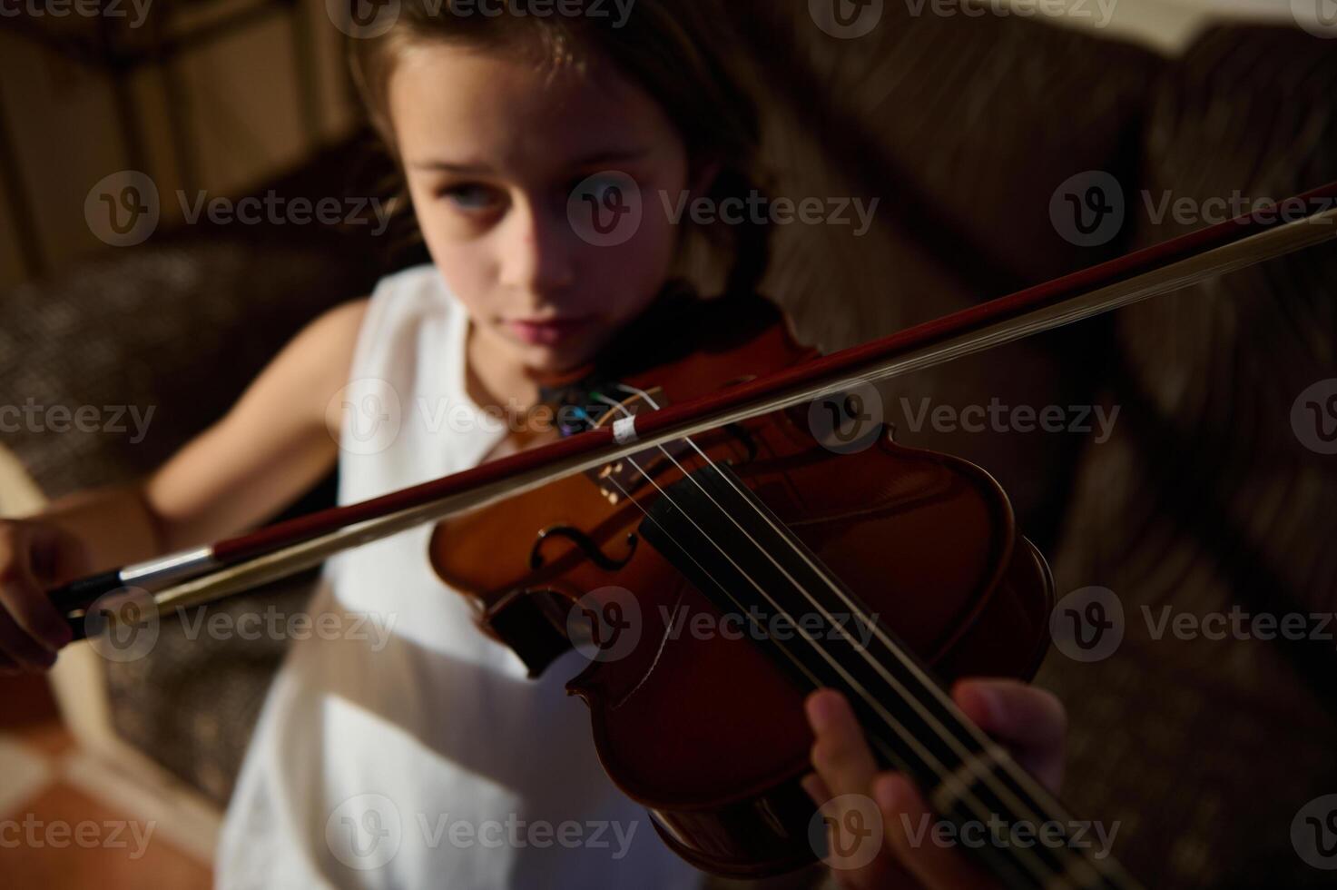 Young girl practicing violin at home with focus and determination photo