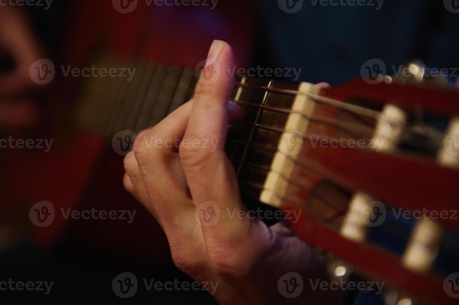 Close-up of hands playing an acoustic guitar, showcasing finger placement and chord strumming for an intimate and artistic musical moment photo