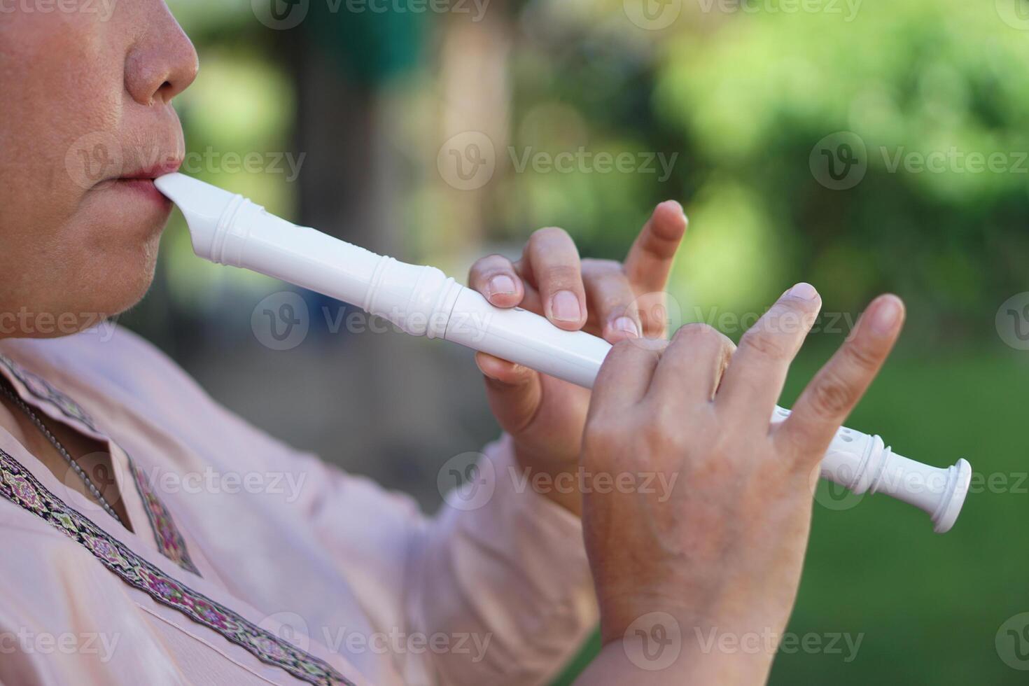 Close up woman flutist, musician is playing a recorder flute. Concept, music blowing with mouth, control with fingers on holes of flute for melody and rhythm. Mouthpiece musical instrument. photo
