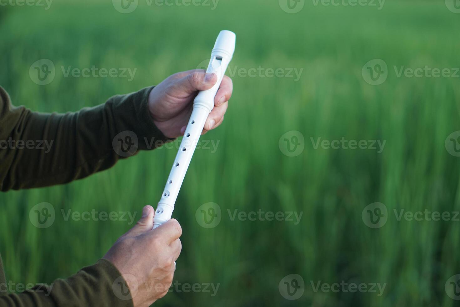 Close up hands hold a white recorder flute. Concept, music blowing with mouth, control with fingers on holes of flute for melody and rhythm. Mouthpiece musical instrument. photo