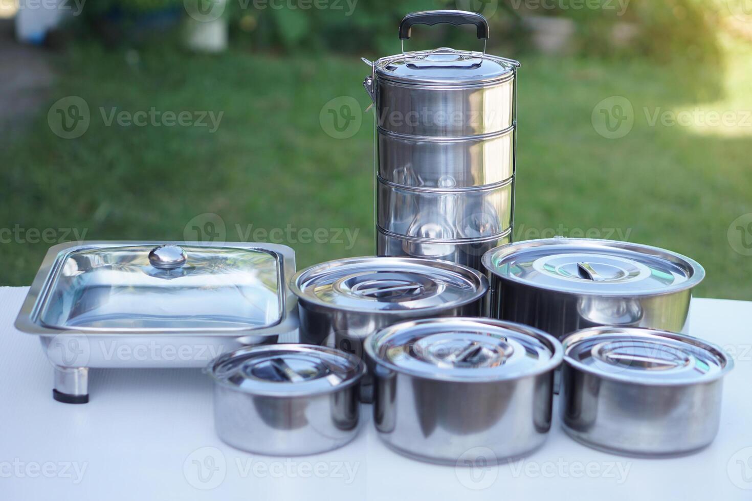 Set of stainless steel cookware and kitchen utensils. Pots, tray and tiffin box for containing food. Concept, preparing equipment for eating out. Picnic. photo