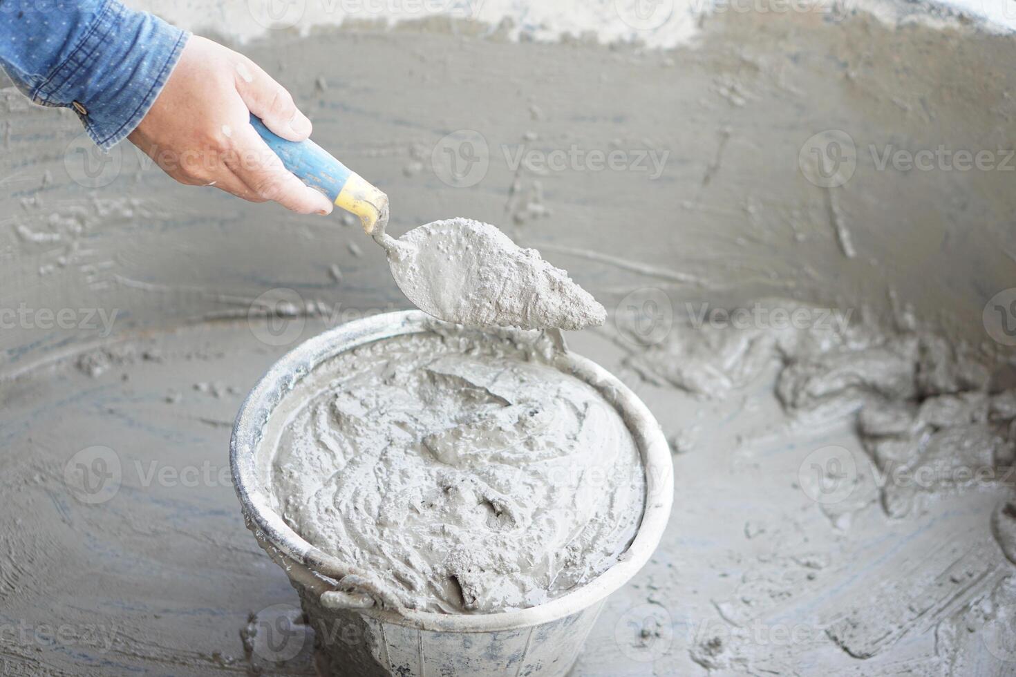 Close up worker hand hold a trowel to mix wet cement in bucket. Concept. Construction job. Process of construction work with cement. Choose good quality and proper material product for building photo